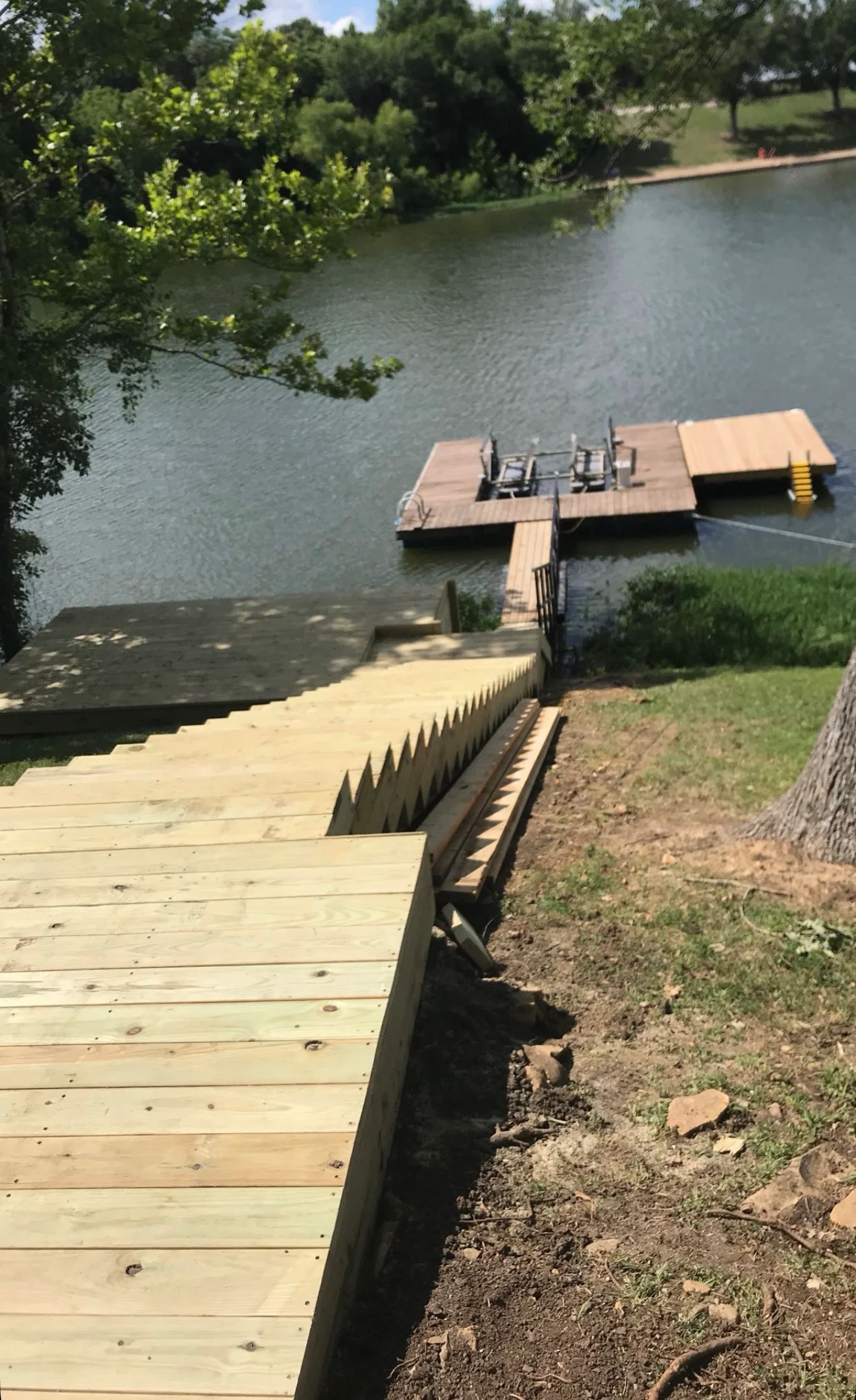Newly stained wooden deck and floating dock on water with protective railings and stairs