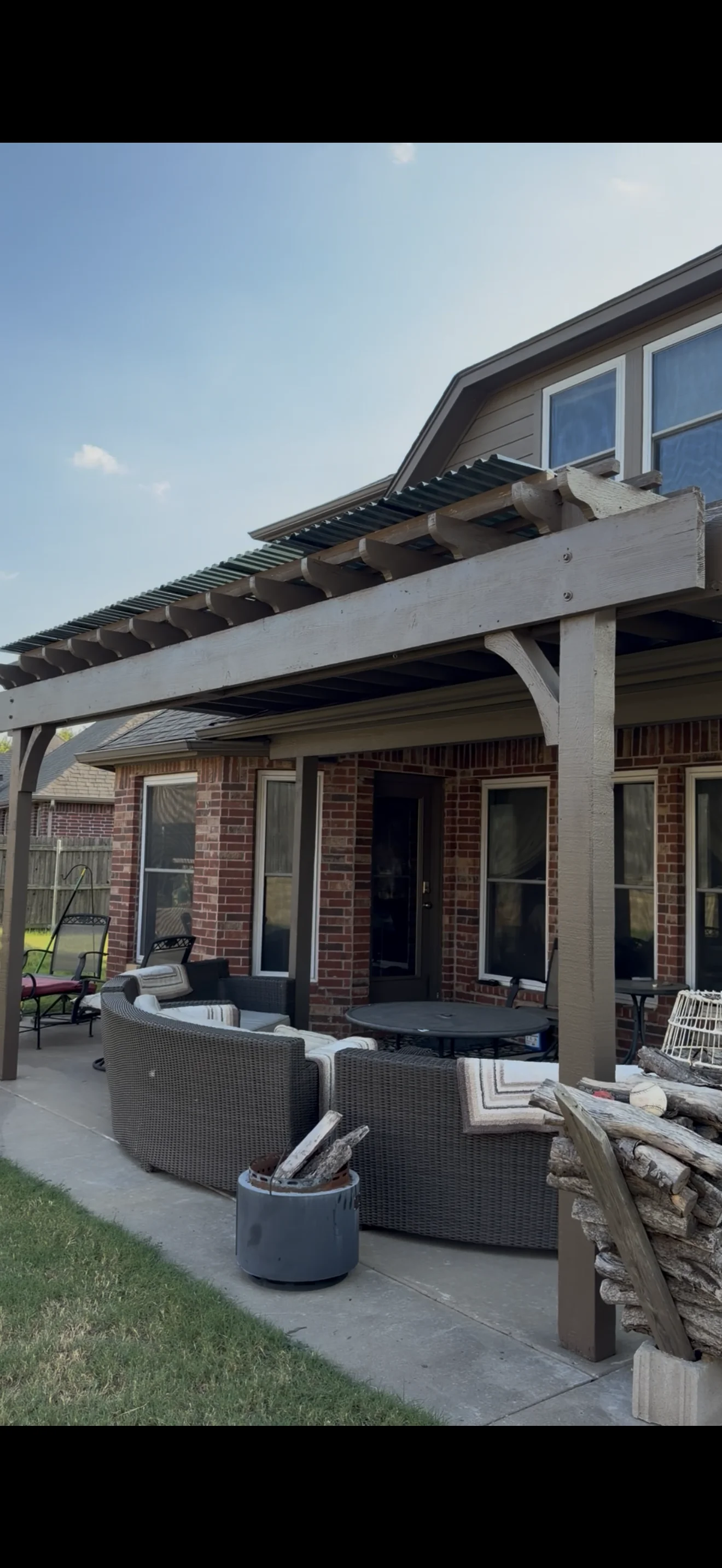 White painted pergola with slats over brick patio and outdoor seating area