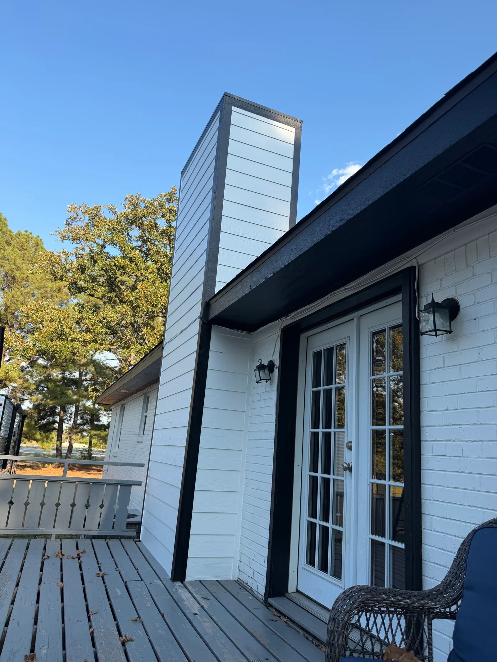 White horizontal siding with black trim and painted chimney on modern home exterior