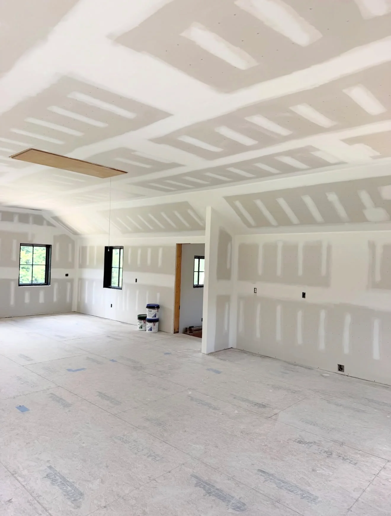 Finished drywall interior with vaulted ceiling, skylights, and prepared walls ready for painting