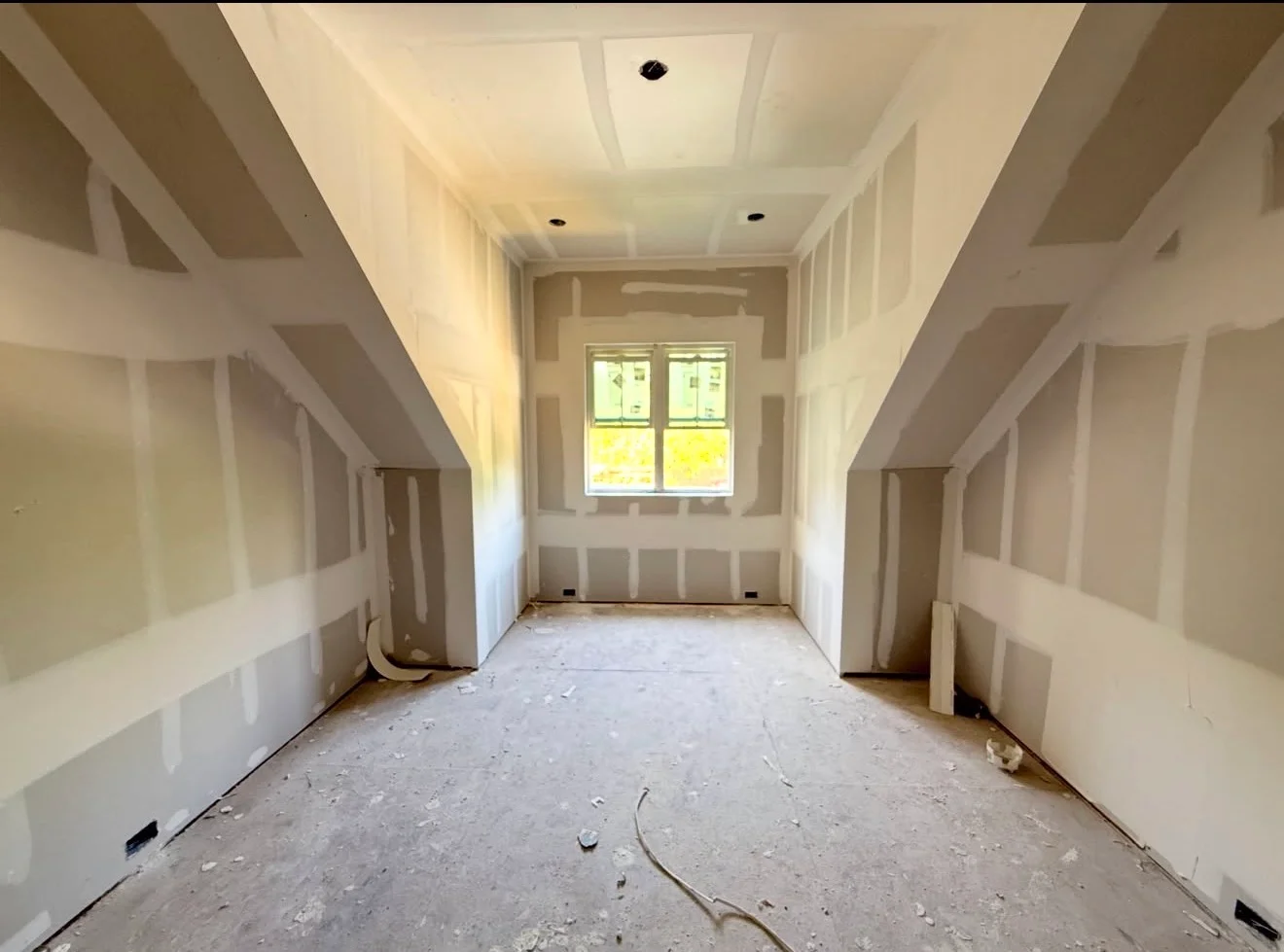 Finished attic room with drywall, coffered ceiling, recessed lights, and primed walls