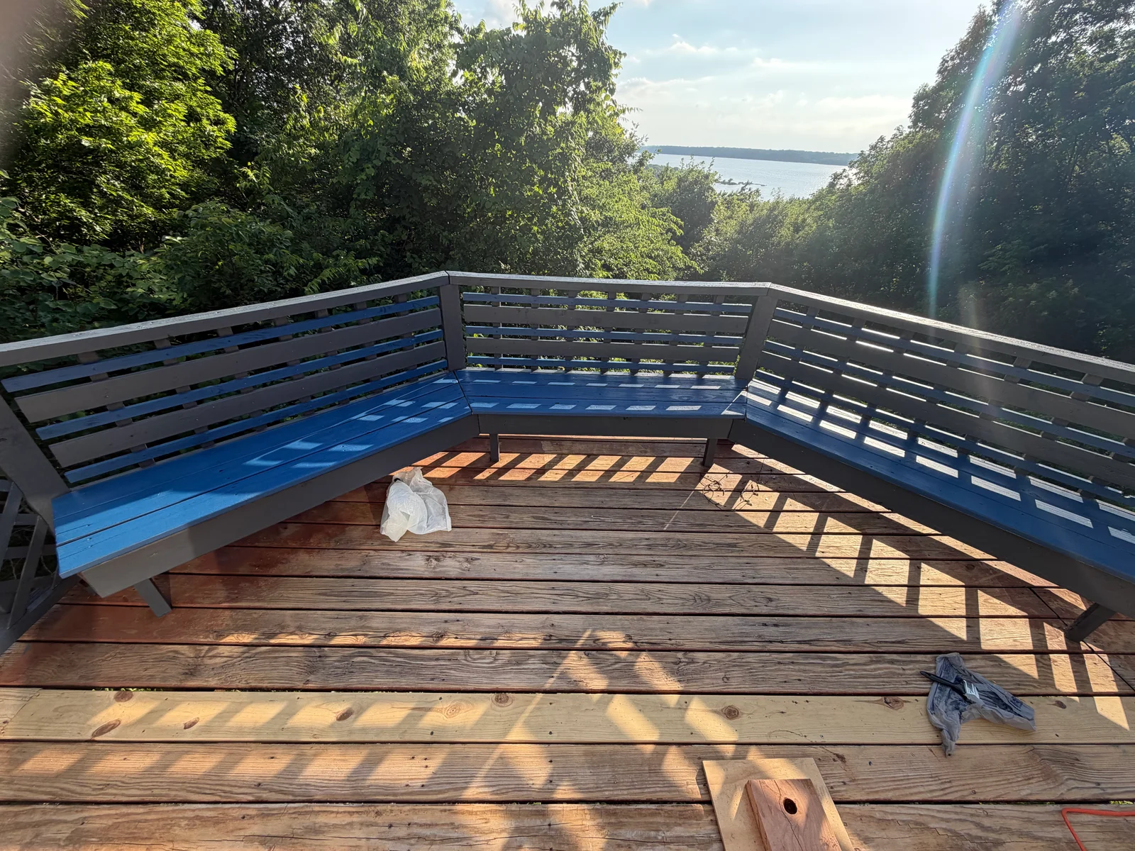 Painted blue deck railing and bench seating with horizontal slats overlooking water and trees