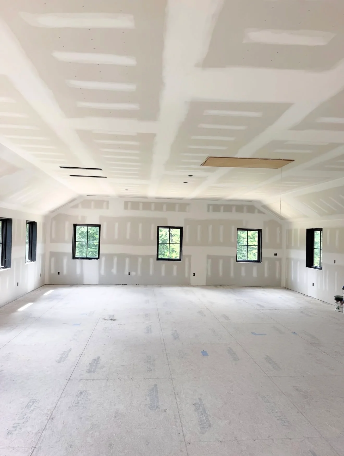 Finished drywall walls and coffered ceiling with recessed lighting in open interior space