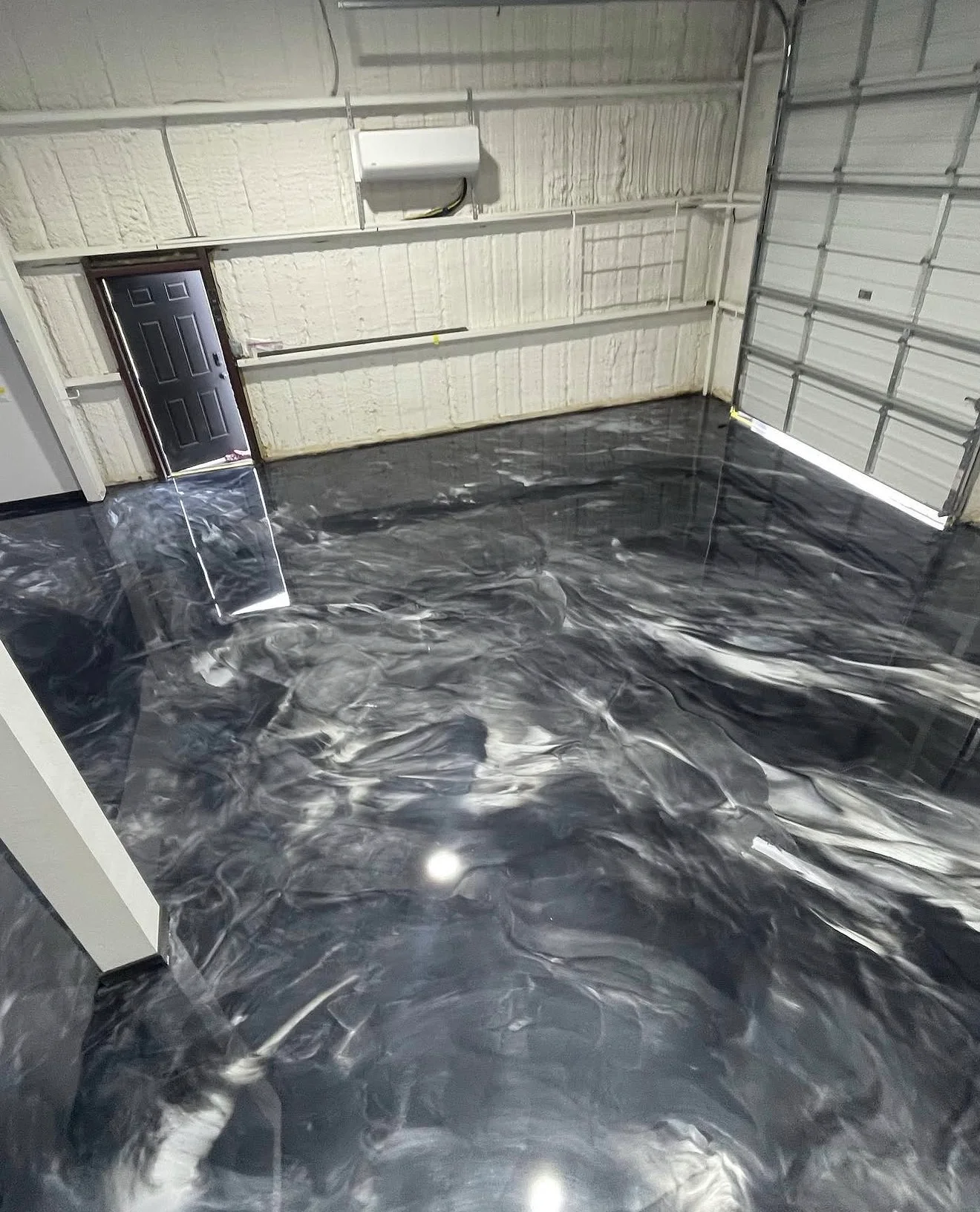 Garage floor with black and gray marble-pattern epoxy coating, high-gloss finish