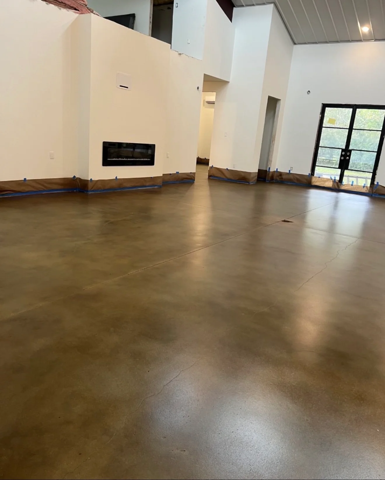 Polished concrete floor coating in commercial space with white walls and protective masking