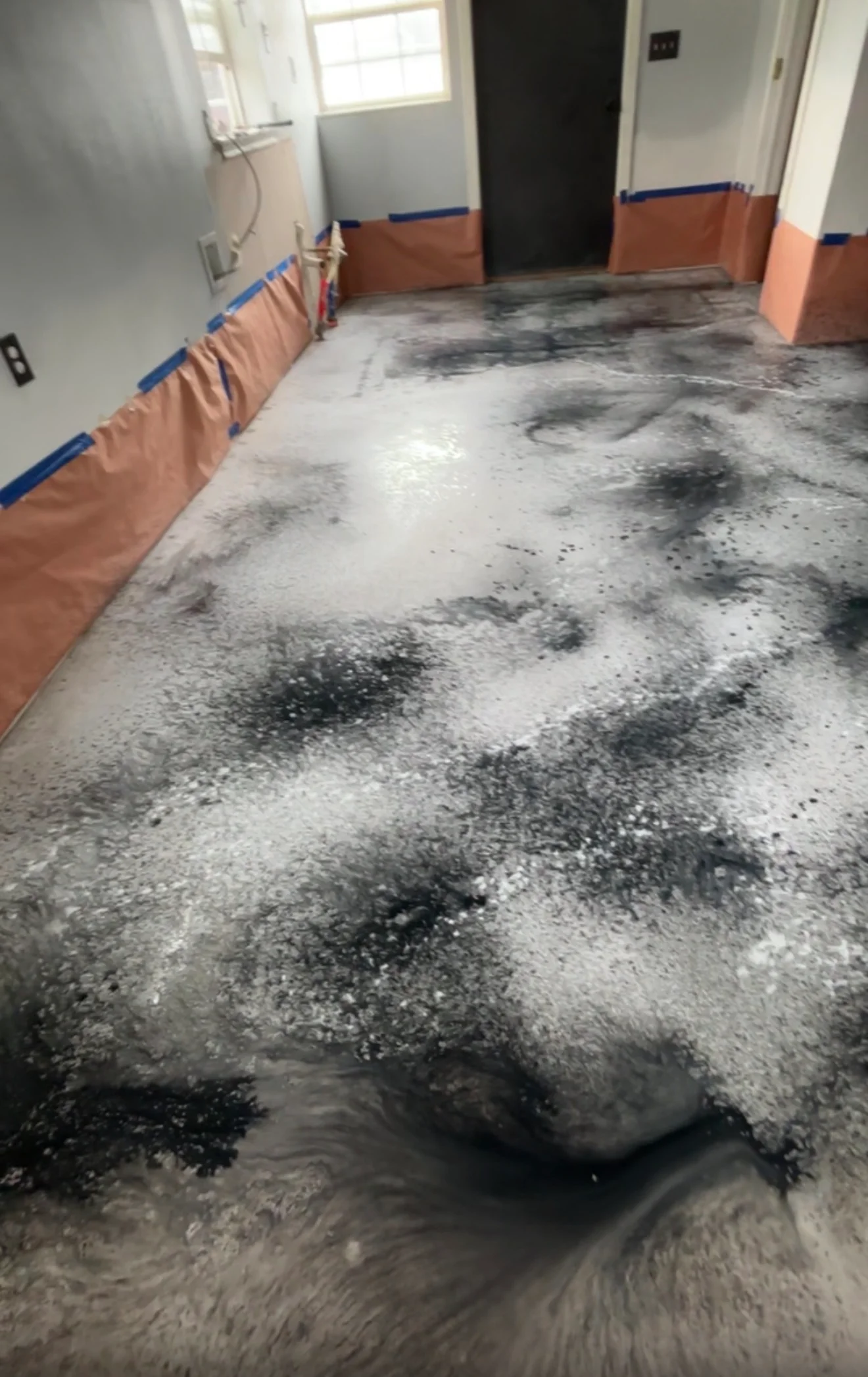 Concrete floor with gray primer, protective kraft paper and blue tape masking along walls
